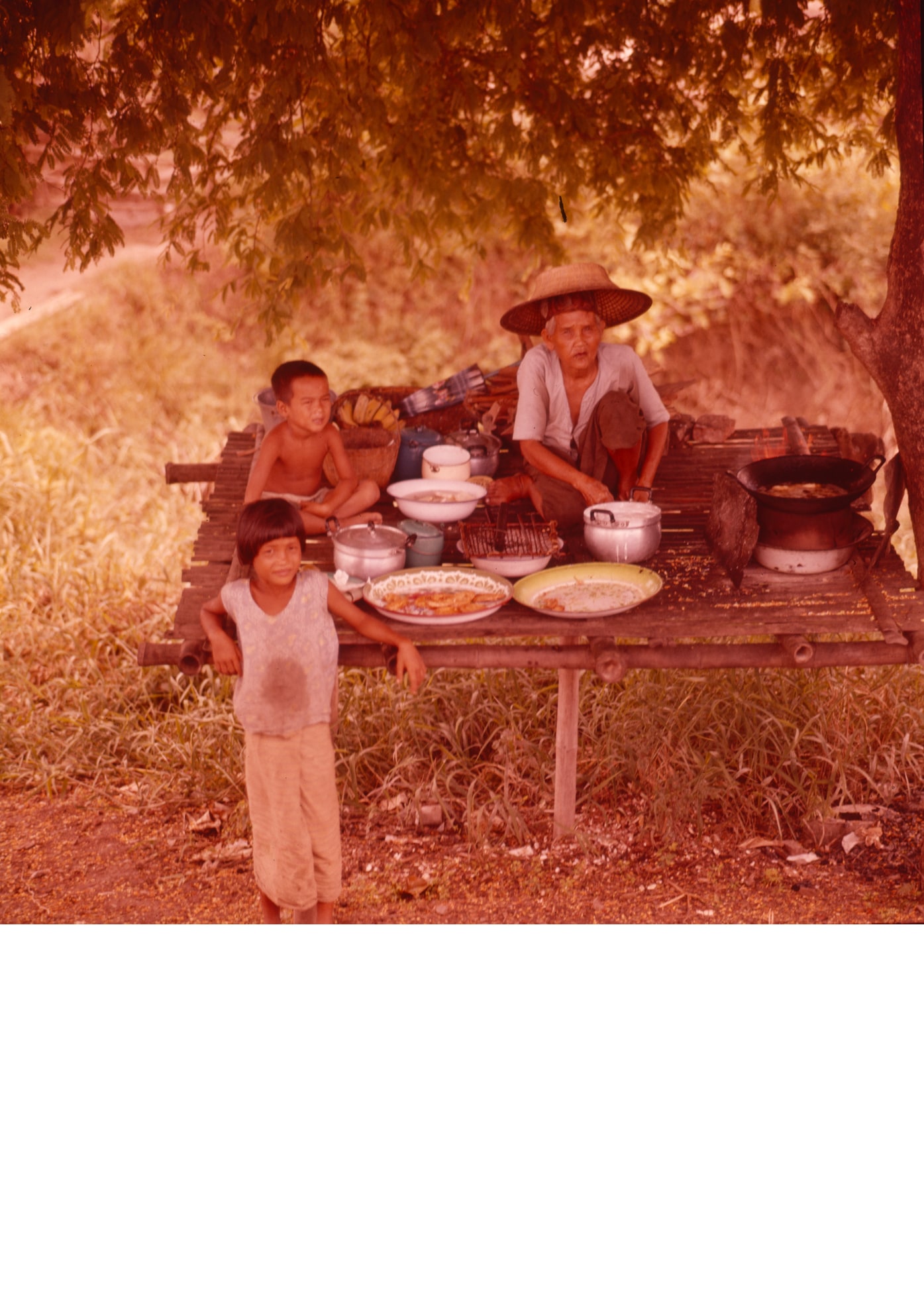 Ein Mann und zwei Kinder während einer Mahlzeit im Freien, Asien (1960er Jahre). Foto: Otl Aicher. © Florian Aicher Rotis, HfG-Archiv / Museum Ulm. HfG-Ar Ai D o. Si.